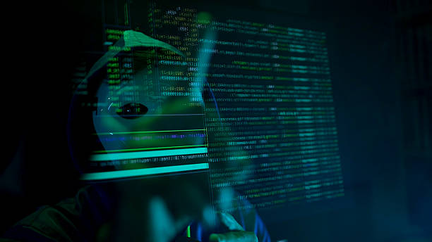 istock Anonymous hacker wearing a mask and hoodie interacting with digital data in a dark room 2241533382