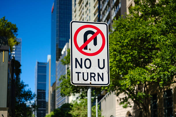 No u turn sign with city view behind on a sunny day.