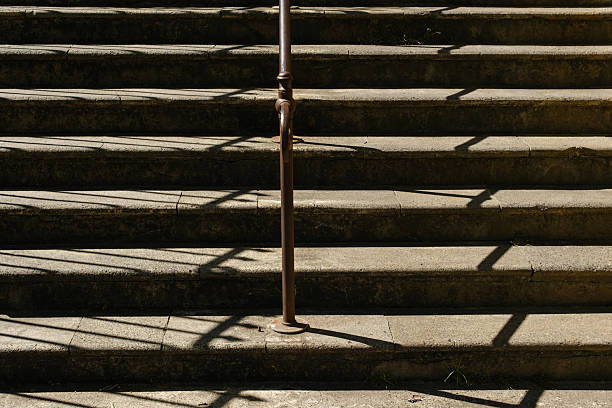 Old concrete outdoor stairs with handrail on a sunny day.