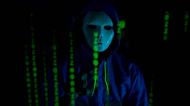 istock Anonymous hacker wearing a mask and hoodie interacting with digital data in a dark room 2241533641