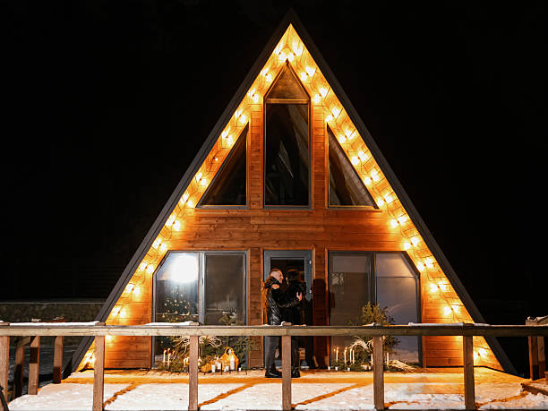 istock Couple hugging in front of illuminated chalet at night 2241535854