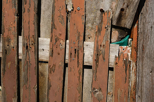 Old damaged brown fence palings on a sunny day.