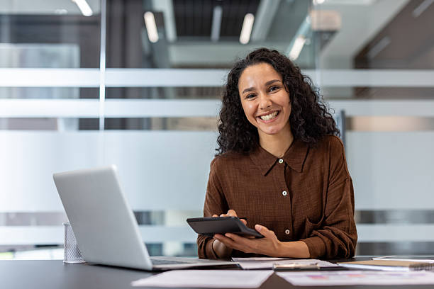 istock Professional businesswoman smiling while calculating finances in modern office 2241541435
