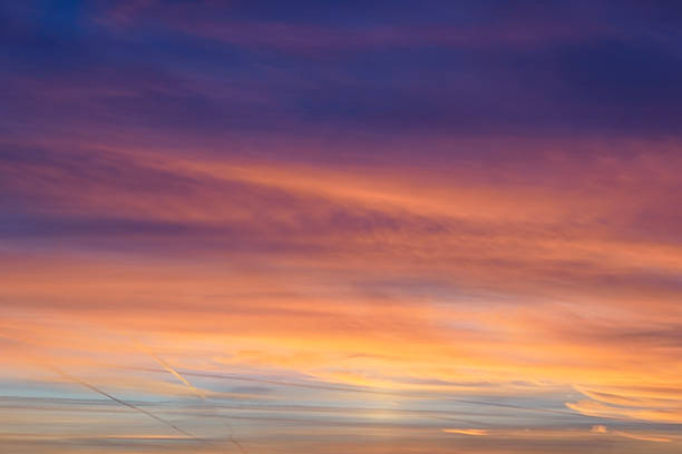 A cloud-filled sky illuminated by the setting sun.