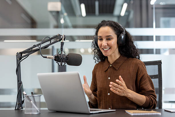 istock Woman broadcasting podcast online using microphone and laptop 2241543566
