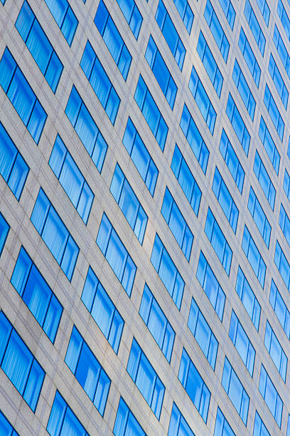 A tilted view of a tall building with repeating blue window panels, forming a bold geometric pattern. The cool blue tones convey modern urbanity and architectural precision across the facade.