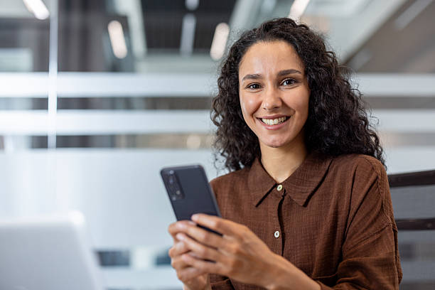 istock Smiling businesswoman using mobile phone in modern office 2241544563