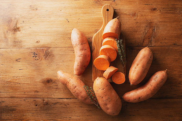 Heap of organic sweet potato or batata on wooden kitchen table top view. Vegan healthy food.