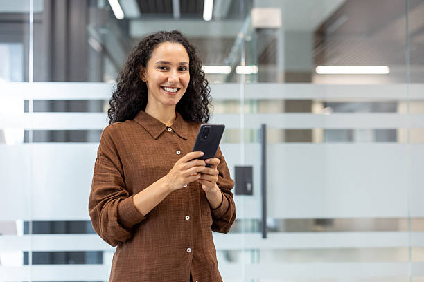 istock Professional woman smiling using smartphone in office 2241548215