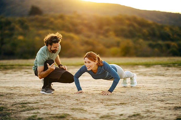 istock Personal trainer helping woman doing push-ups outdoors 2241548551