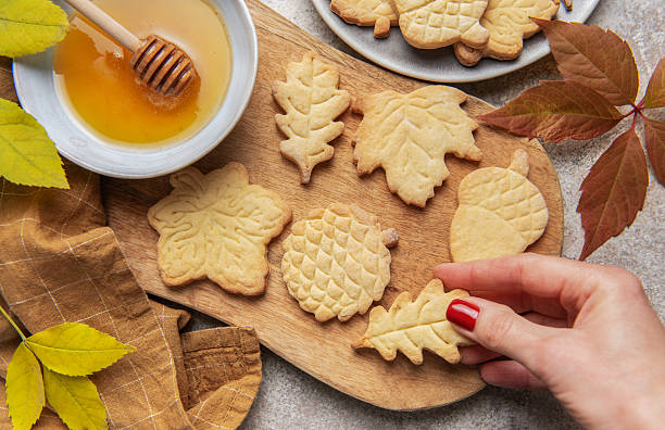 Hand holding fall themed shortbread cookies with honey