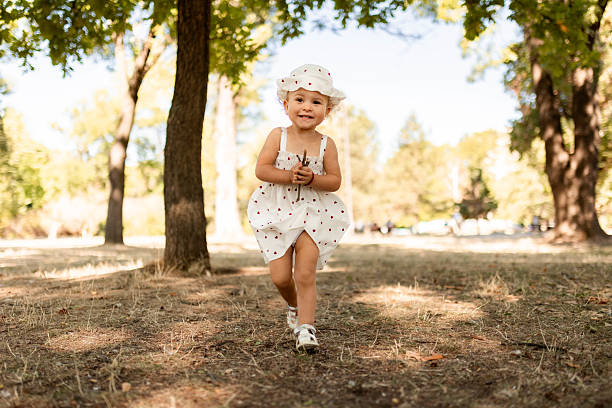 Adorable child strolling along a park path surrounded by greenery and trees.