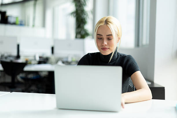 istock Young woman working on laptop in modern office 2241552888