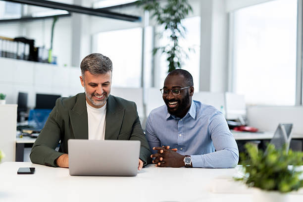 istock Smiling business colleagues collaborating on laptop in modern office 2241552907