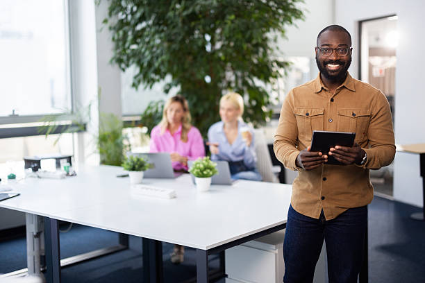 istock Smiling businessman holding digital tablet in modern office 2241552983