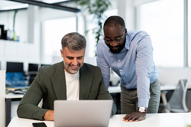 istock Diverse businessmen collaborating on laptop in modern office 2241554425