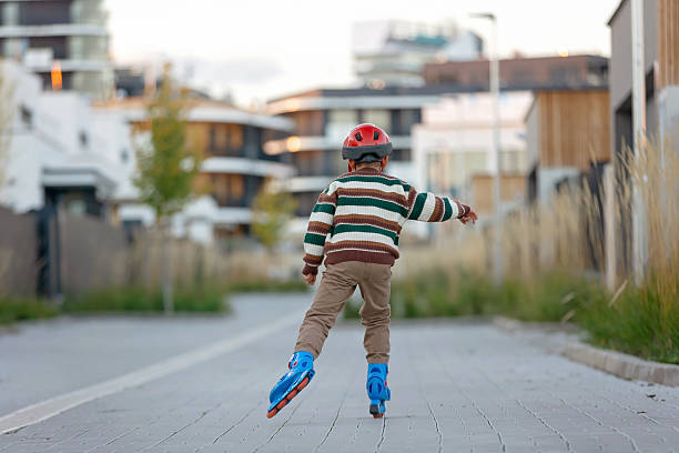 Cute school child, boy, riding roller skates, skating on the street autumntime