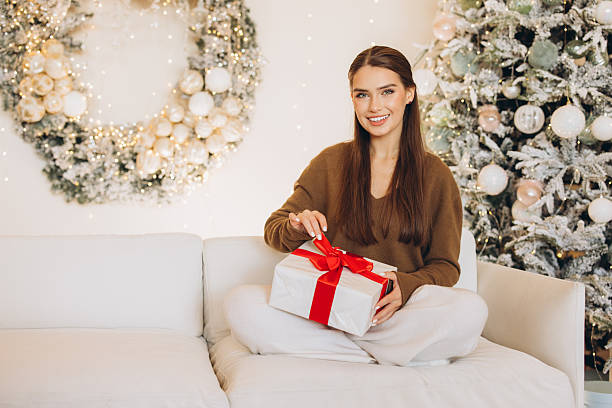 istock Woman Joyfully Opening Gift in Festive Christmas Setting 2241556926