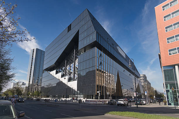 istock Cube Berlin's modern glass architecture - The Cube Berlin, a stunning example of modern architecture, featuring a geometric, reflective glass facade under a blue sky at Washingtonplatz. 2241558566