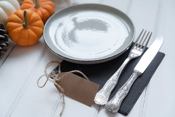 istock A Happy Thanksgiving tag hangs from a small pumpkin and plate as silverware sits on the table 2241558781