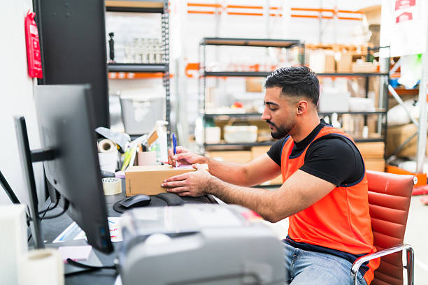 istock Employee filling delivery details on cardboard package. 2241559352