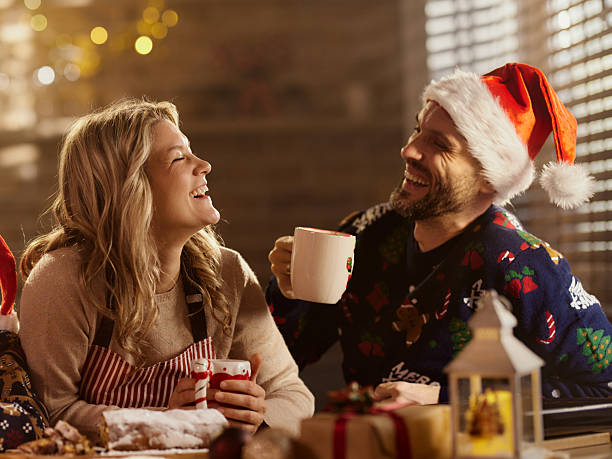 Cheerful couple drinking coffee during New Year in dining room.
