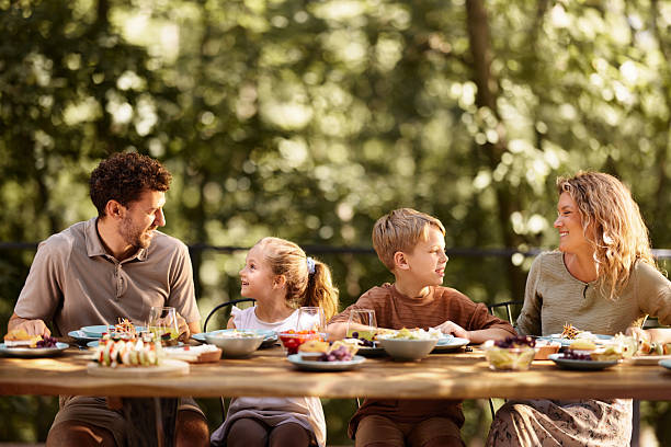istock Happy family talking while having lunch at picnic table on a terrace. 2241560489