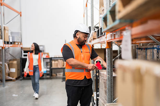 A logistics professional carefully taps and checks a large cardboard parcel inside a warehouse storage facility, reflecting reliability, attention to detail, and smooth supply chain operations.