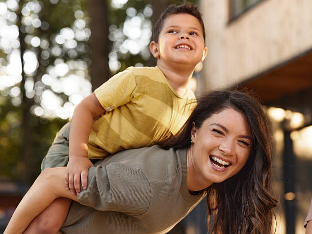 istock Cheerful mother piggybacking her son in the backyard. 2241562620