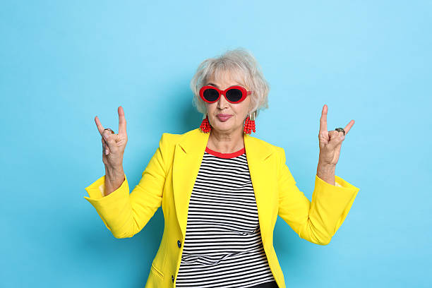 istock Cool grandmother showing rock gesture on light blue background 2241563133