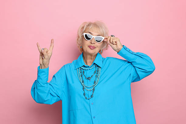 istock Cool grandmother showing rock gesture on pink background 2241563278