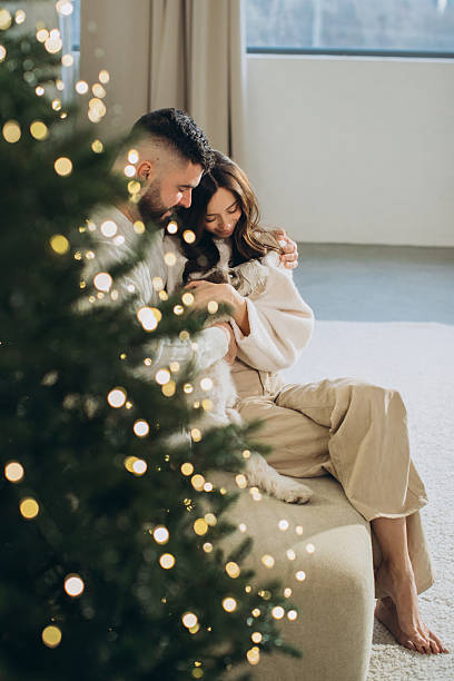 istock Couple embracing small dog by christmas tree 2241563925