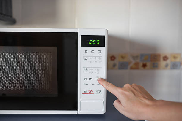 istock Hand pressing buttons on modern microwave oven with digital display 2241567225