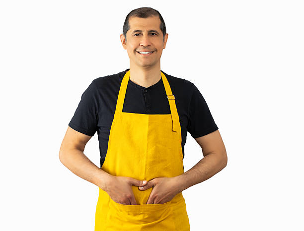 istock Man with yellow apron over white background 2241569604