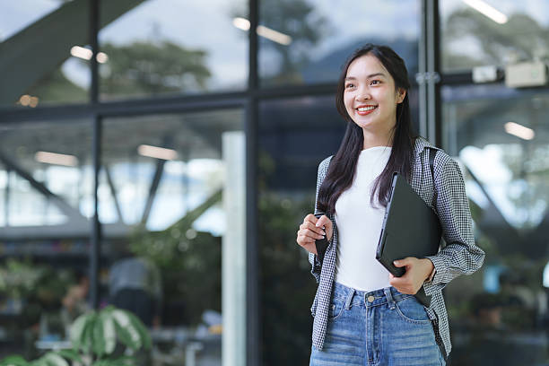 istock Asian woman student walking on campus with laptop 2241572233