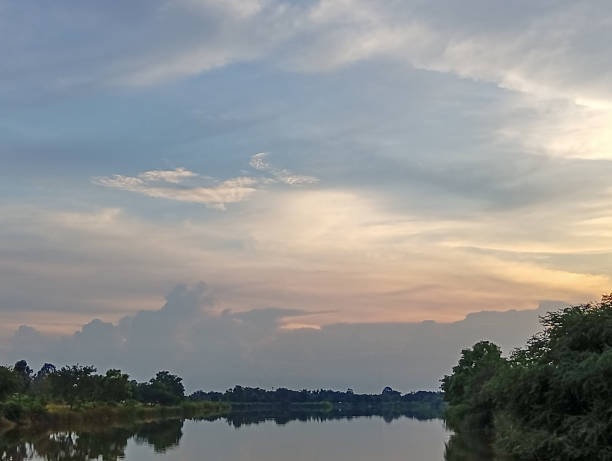 Serene river landscape at sunset with calm water reflecting colorful sky and surrounding trees