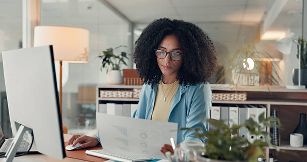 istock Reading, paperwork and woman with computer in office, serious or working late for data entry on web. Online, accountant and African person with glasses for financial report, graphs and tech at night 2241578660