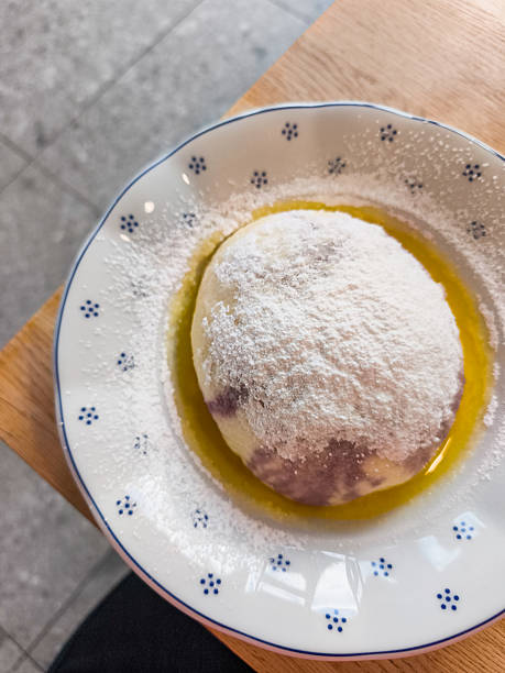 istock Delicious dessert dumpling knedlik with blueberry featuring a round pastry topped with powdered sugar and drizzled with oil 2241580352