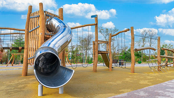 istock Bright and modern playground features a metal slide and climbing frame surrounded by trees on a sunny day 2241580985