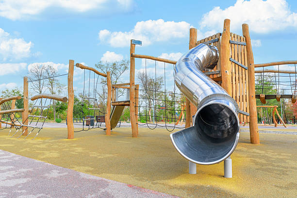 istock Bright and modern playground features a metal slide and climbing frame surrounded by trees on a sunny day 2241581026