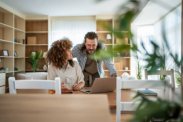 istock Couple smiling while working on laptop together at home 2241584914