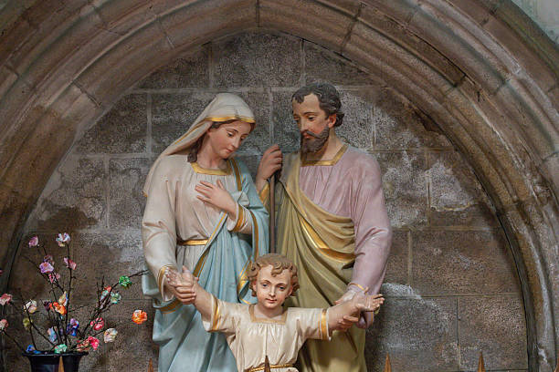 Ancient stone statue of Virgin Mary with the baby Jesus Christ against white background. Religion, faith, eternal life, God concept.