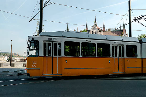 Budapest, Hungary - April 23, 2018 - Historic yellow tram in budapest passing gothic architecture.