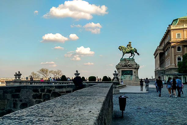 Budapest, Hungary - April 24, 2018 - Historic statue in buda castle courtyard with tourists on a sunny day.