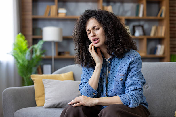 istock Young woman suffering from strong toothache at home 2241590621