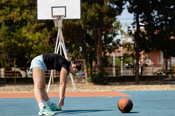 istock Basketball player stretching on court preparing for practice in sunny outdoor setting 2241590843