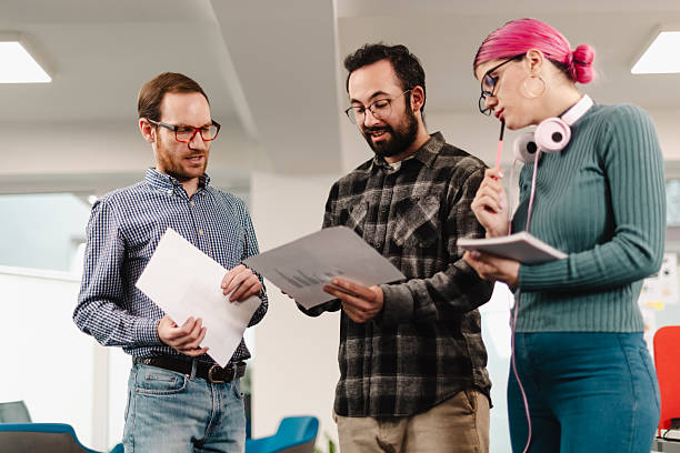 istock Businesspeople collaborating in an office environment while reviewing documents and discussing ideas in a modern workspace 2241591357
