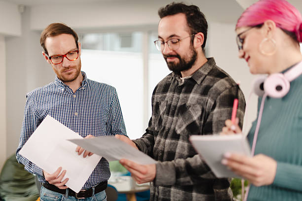 istock Businesspeople collaborate in a modern office space while reviewing project documents and discussing ideas in a creative atmosphere 2241591374