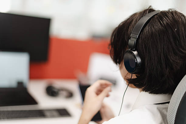 istock Business professional focusing on tasks while wearing headphones in a modern office setting with technology around 2241591403