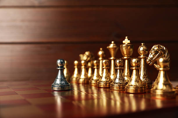 istock Silver pawn in front of other chess pieces on chessboard. Competition concept 2241592848